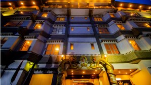 Un hotel de varios pisos con un diseño arquitectónico tradicional, con balcones y una entrada destacada con detalles decorativos.