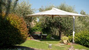A patio area with a white umbrella, wicker furniture, and a well-maintained lawn.