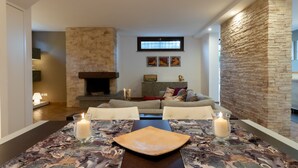 A dining area with a table set for two, a fireplace, and a stone accent wall.