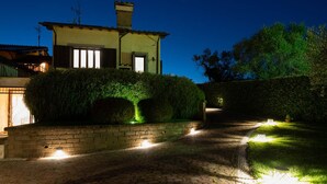 A house with a paved driveway, a brick wall, and a well-lit pathway.