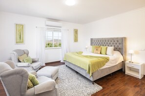 A bedroom with a bed, a chair, a nightstand, and a window with curtains. - Villa Botanica - Amazing villa with private pool (Silves)