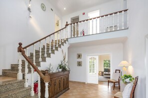 A spacious living area with a wooden staircase, a fireplace, and a dining area.