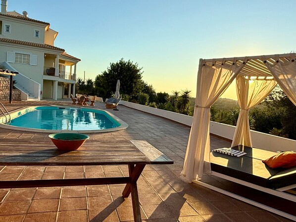 A rooftop pool area with a pool, lounge chairs, and a canopy.