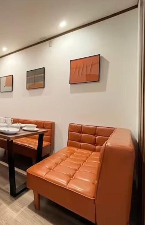 A modern room with a leather sofa, a dining table with chairs, and framed artwork on the wall. - Ikemune Bldg. 2F (Osaka)