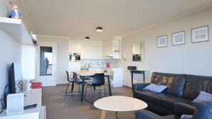 Una sala de estar moderna con un sofá, una mesa de comedor y una cocina al fondo.