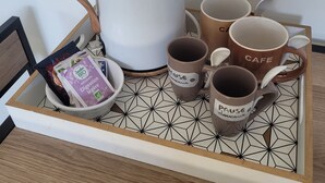 Una bandeja con una cafetera, cuatro tazas de café y un sobre de leche para café.