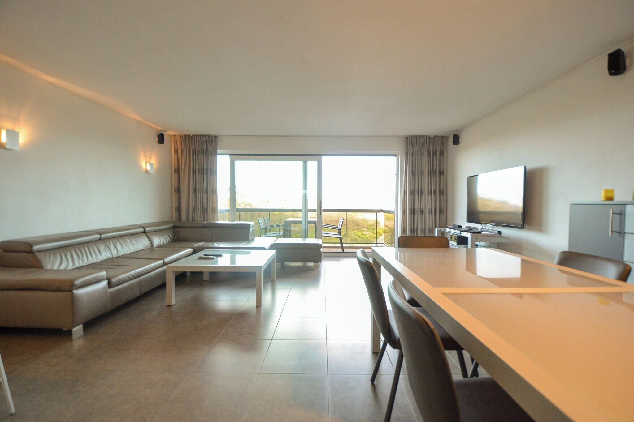 Een moderne woonkamer met een bank, salontafel en eettafel.