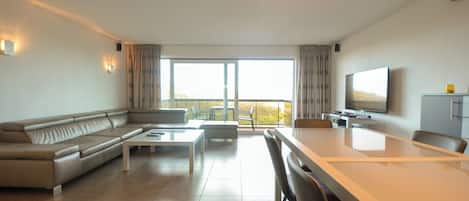 Een moderne woonkamer met een bank, salontafel en eettafel.