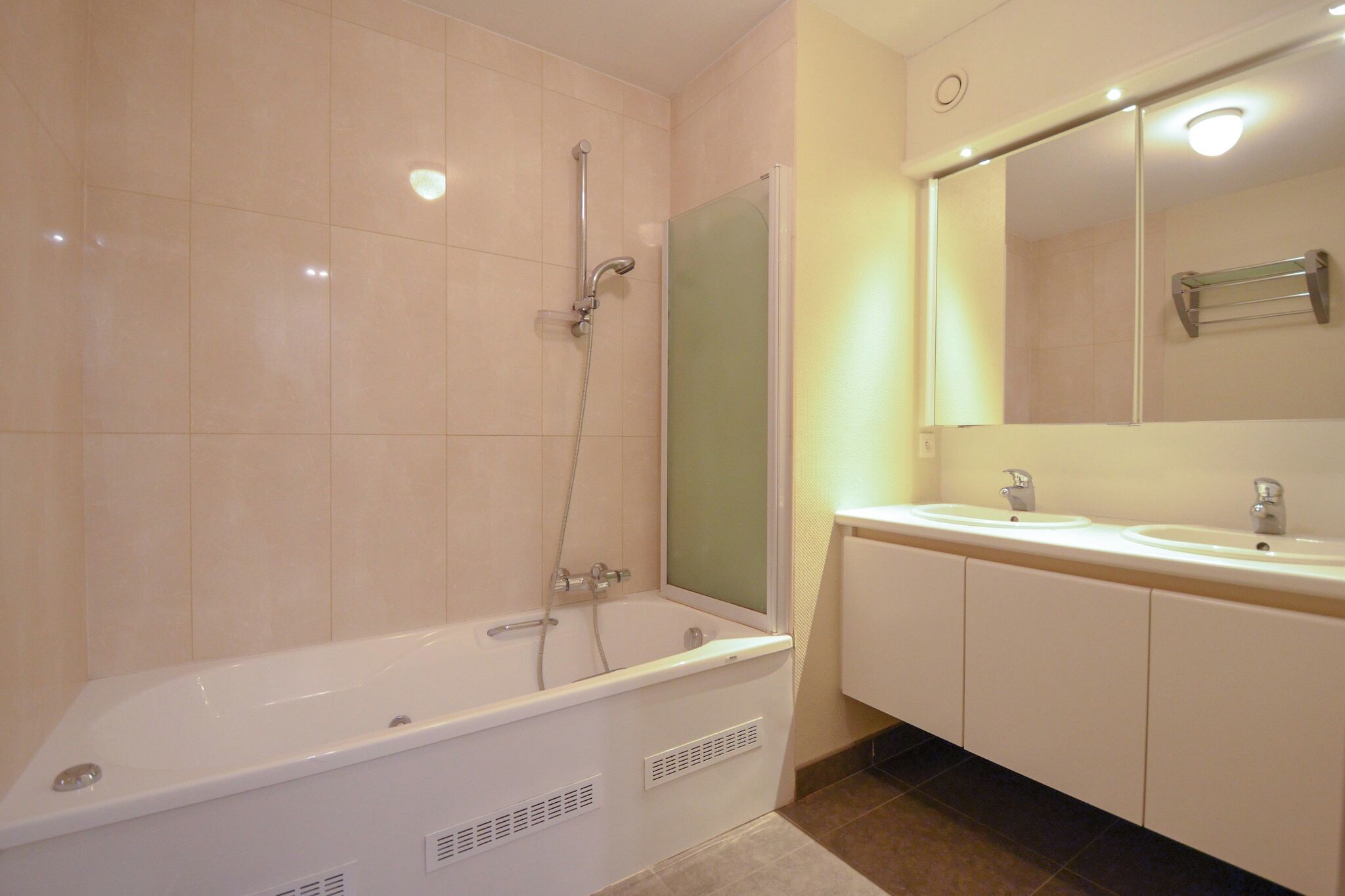 A bathroom with a bathtub, two sinks, and a mirror.