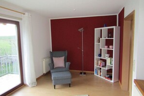 A living room with a grey armchair, a white bookshelf, and a floor lamp.