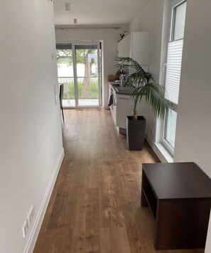 Un couloir étroit, doté d’un plancher en bois, mène à une porte-fenêtre coulissante.