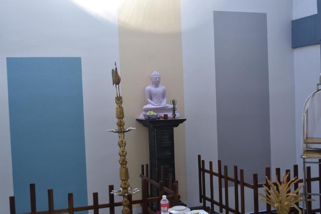 A room with a Buddha statue, a decorative pillar, and a small altar with incense.
