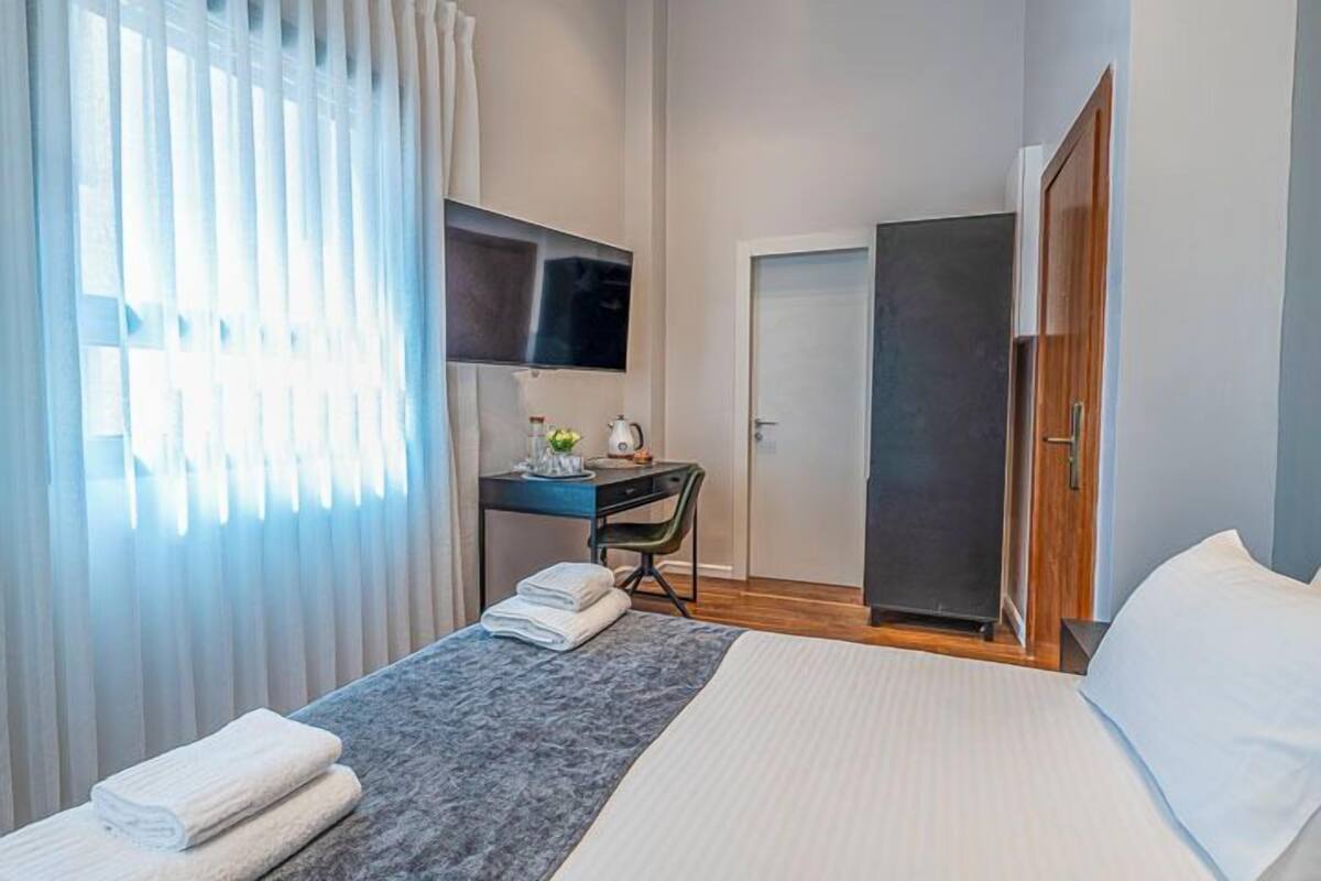 Ein Hotelzimmer mit Bett, Schreibtisch, Stuhl, Fernseher und Kleiderschrank.