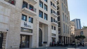 Un hotel con fachada de piedra, varios balcones y zona de estar al aire libre.
