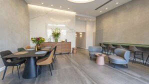 Un comedor moderno con pared de mármol, mueble de madera y una mesa redonda con sillas.