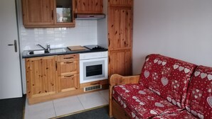 Una cucina compatta con mobili in legno, forno integrato e lavandino.