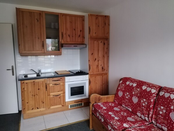 A compact kitchen with wooden cabinets, a built-in oven, and a sink. - Studio Dans Résidence Avec Piscine Couverte (Les Rousses)