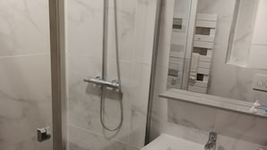 Un bagno moderno con doccia vetrata, lavandino bianco e mobile bagno con specchio.