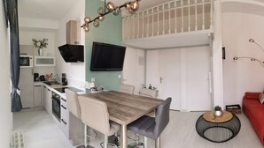 A modern kitchen with a dining area, a red sofa, and a wall clock.