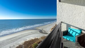A balcony with a view of the beach and ocean.