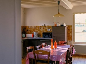 A dining area with a table set for four, a kitchen in the background, and a window with a view.