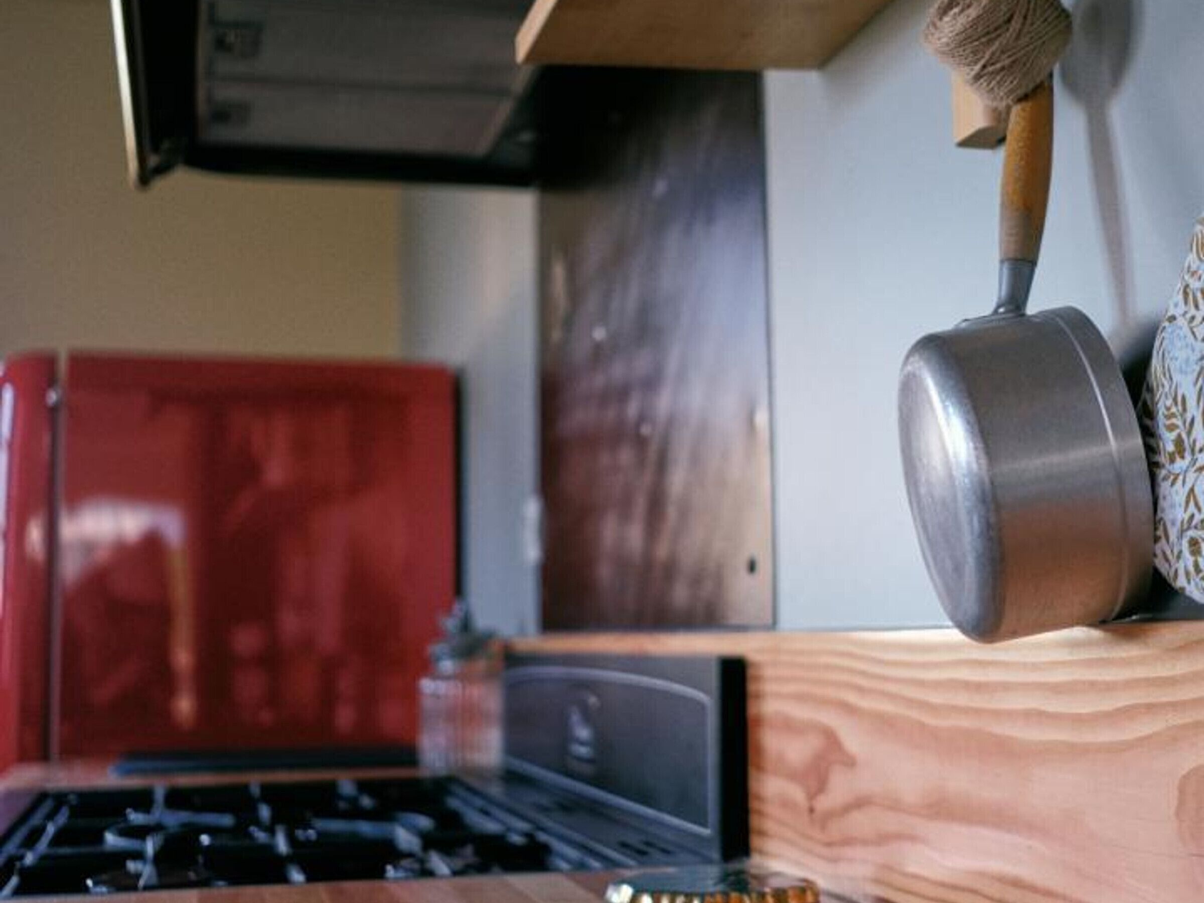 A kitchen with a wooden countertop, a stove, and a hanging pot rack.