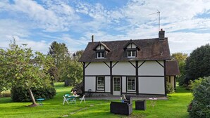 Une maison de style Tudor traditionnel, dotée d’une pelouse bien entretenue et d’un espace extérieur aménagé pour s’asseoir.