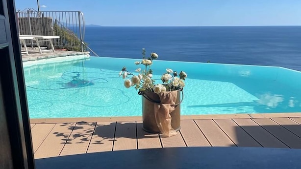 En vy över en pool med en klarblå himmel och havet i bakgrunden.