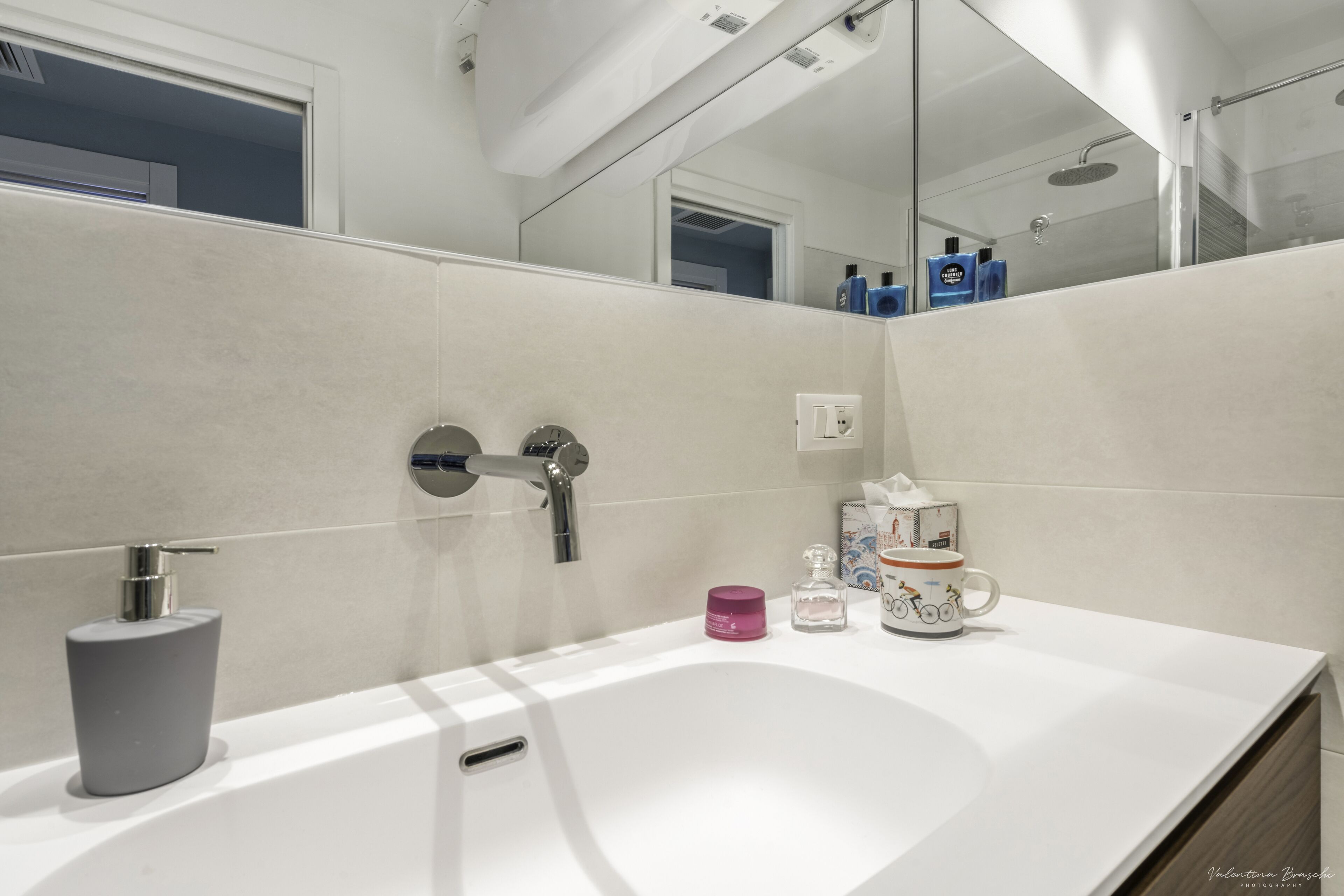 Une salle de bain moderne avec un lavabo blanc, un miroir et une douche.