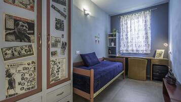 Un dormitorio con cama, escritorio y armario.