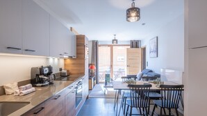 Une cuisine moderne équipée d’une machine à café, un coin repas avec une table et des chaises, et une vue sur l’extérieur.