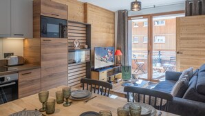 Une cuisine moderne avec des meubles en bois, un four à micro-ondes de marque Bosch et un coin repas avec une table en bois, mise pour quatre personnes.