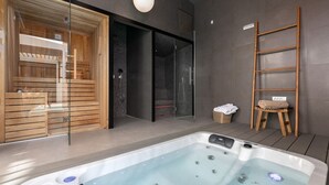 A modern spa area with a hot tub, wooden sauna, and a glass-enclosed shower.