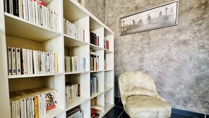A room with a bookshelf filled with books, a chair, and a framed picture on the wall. - Holiday home wild coast la Chaume (Les Sables-d´Olonne)