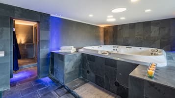 Relax in a spacious bathtub with multiple jets, adjacent to a walk-in shower with a glass enclosure.