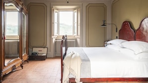 Un dormitorio con una cama grande, un armario de madera, un espejo y una ventana con vistas al exterior.