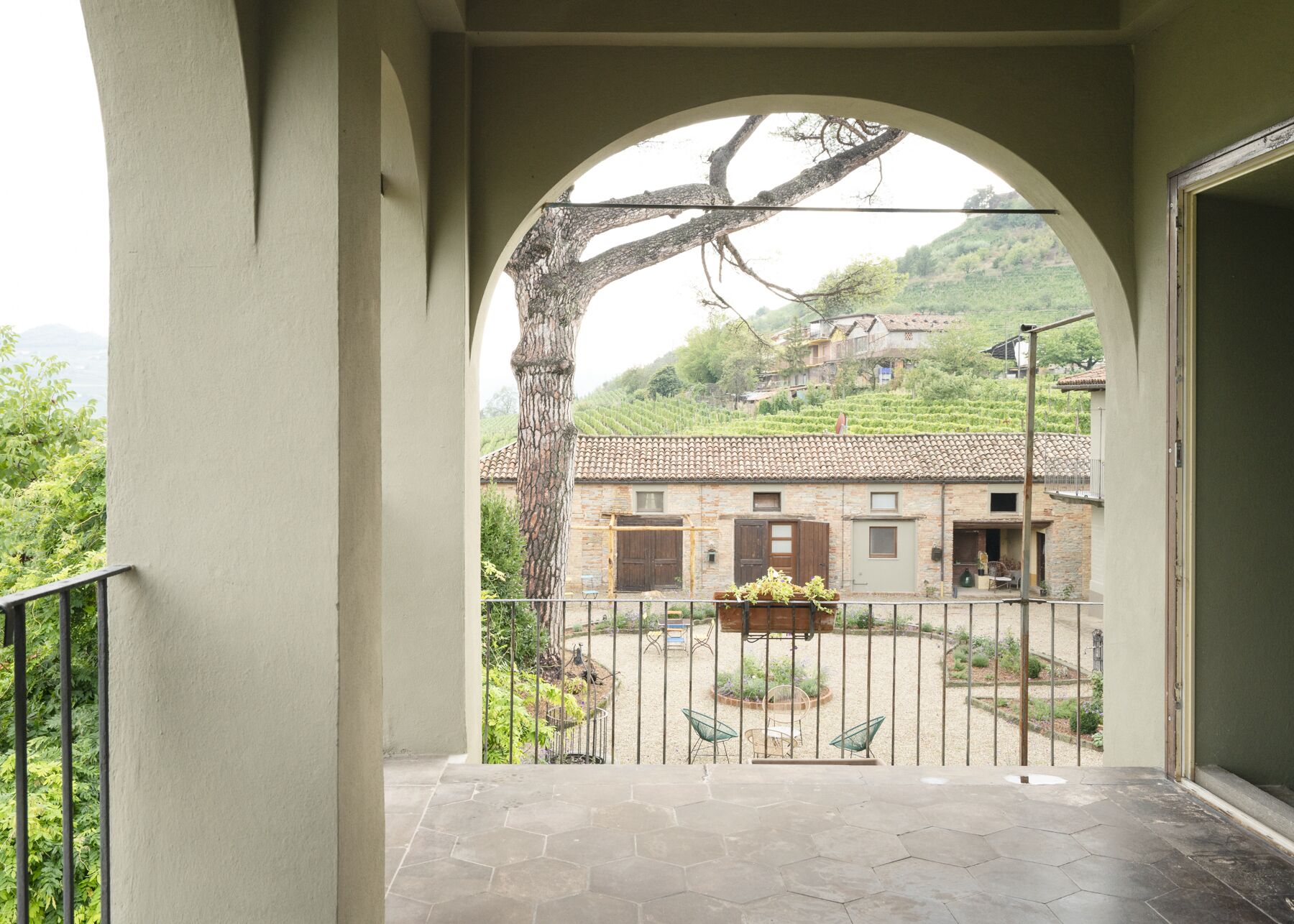 Un balcón con vistas a un viñedo y un edificio de piedra.