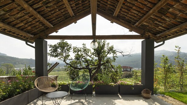 Un área de estar al aire libre cubierta con vistas a un viñedo y colinas.