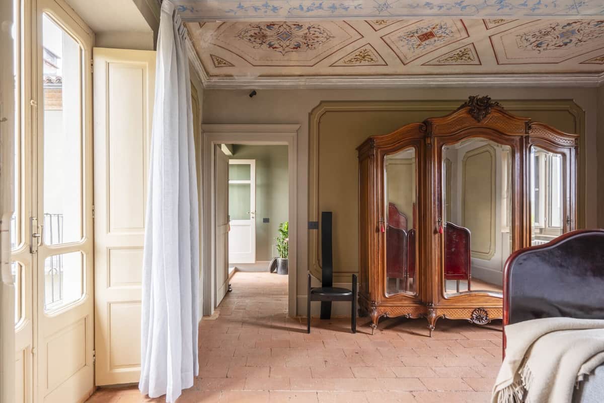 Una habitación con un armario grande de madera, una silla y una cama.