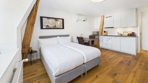 Ein modernes Schlafzimmer mit einem großen Bett, einem kleinen Schreibtisch und einer Küchenzeile.