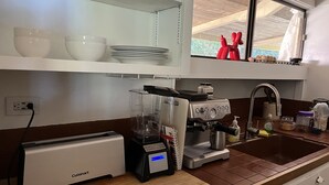 Ett kök med en brödrost, en mixer, en kaffebryggare och ett handfat.