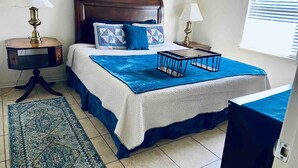 A bedroom with a large bed, two bedside tables, a nightstand, a blue rug, and a wooden headboard. - Sapphire- Welcome large groups, TV’s in all BRMS, Pet Friendly

 (Tyler)