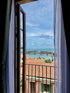 A view from a window with a view of a coastal area, including a bridge and buildings with red-tiled roofs. - Sea Sunset Hotel (Phu Quoc)
