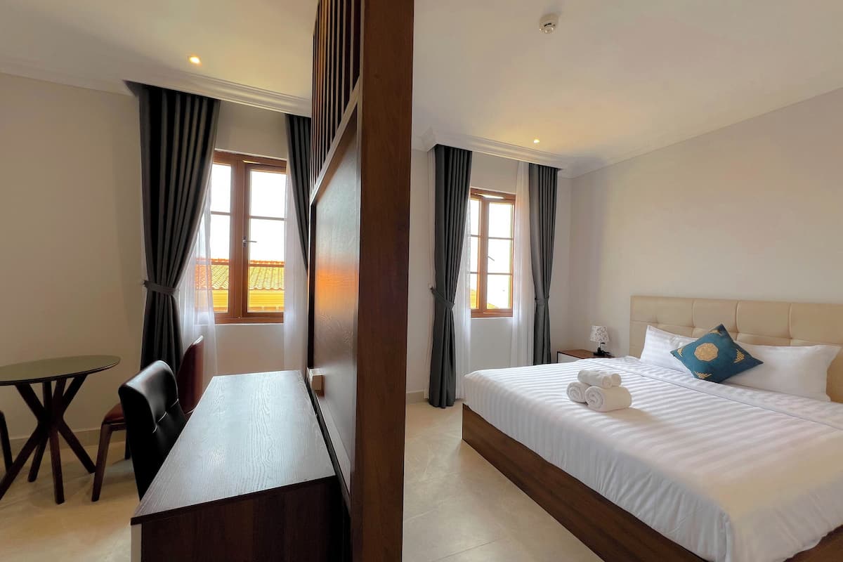 A hotel room with a bed, a desk, and a chair.