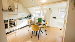 Cozinha moderna com área de jantar, teto estilo loft, piso de madeira e ilha central com cadeiras.