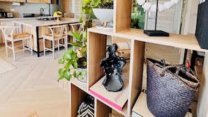 A modern kitchen with wooden cabinets, a central island, and a variety of plants.