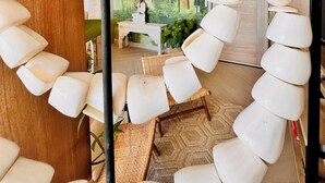 A room with a unique ceiling design featuring a white rope-like structure. There is a wooden floor and a seating area with white chairs.
