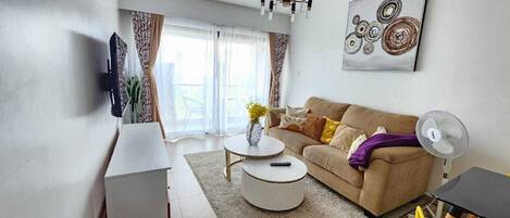 A modern living room with a sofa, coffee table, and a TV mounted on the wall.