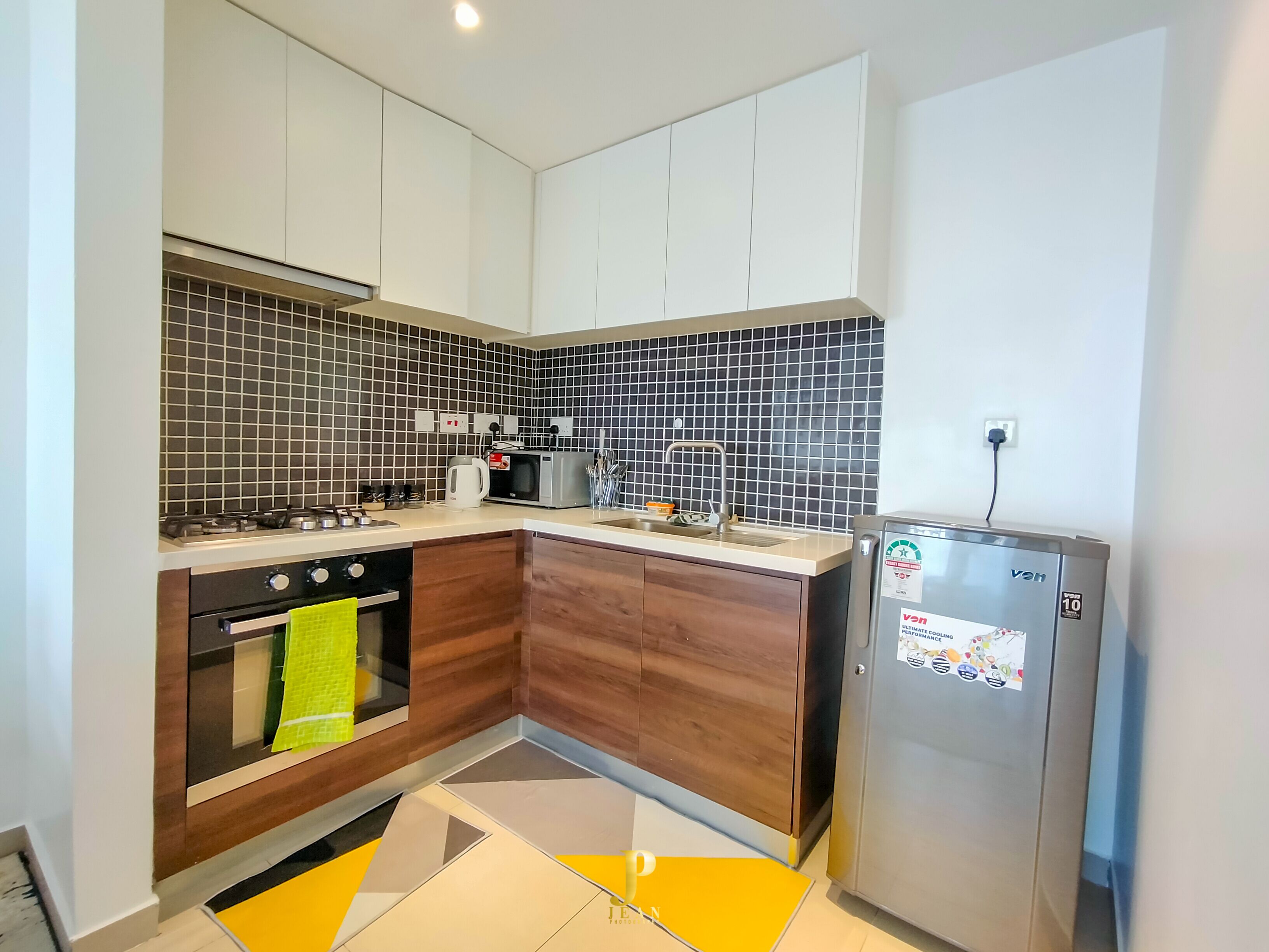A compact kitchen with a gas stove, oven, microwave, and a refrigerator.