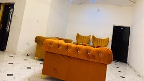 A room with a tufted orange sofa, a black door, and a white ceiling with a modern light fixture. - Flenjo Zone Bar and Apartments (Ado Ekiti)